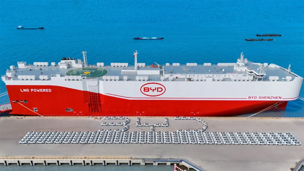 El portacoches más grande del mundo BYD Shenzhen impulsado por GNL atracado en un puerto, rodeado de vehículos eléctricos alineados.