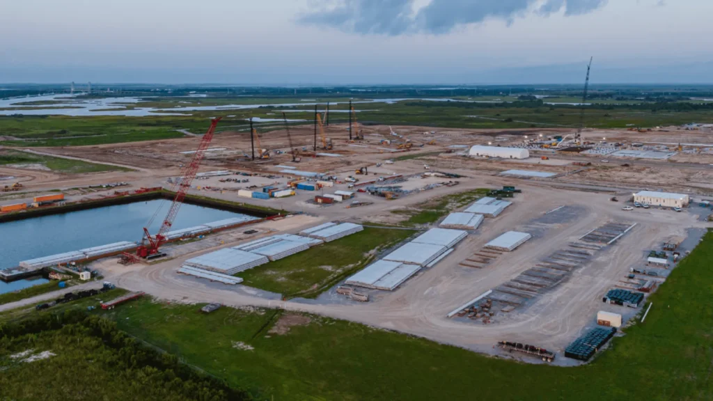 Vista aérea del proyecto LNG en Luisiana y sus obras de construcción en terreno costero con grúas, materiales prefabricados y canales.