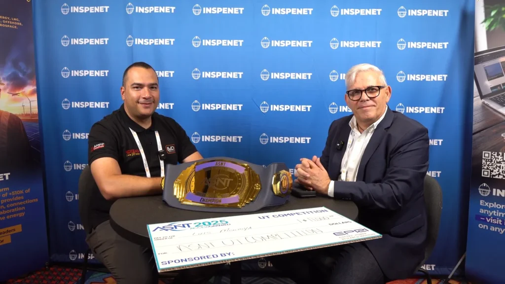Luis Montoya y Francesco Solari durante una entrevista en ASNT 2025, mostrando el cinturón de campeón de ultrasonido industrial y el cheque del premio.